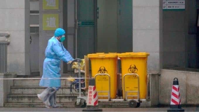 A biohazard waste bin is wheeled out from a hospital in Wuhan. Credit: AP